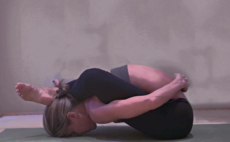 Elizabeth practicing Supta Kurmasana - sleeping tortoise pose